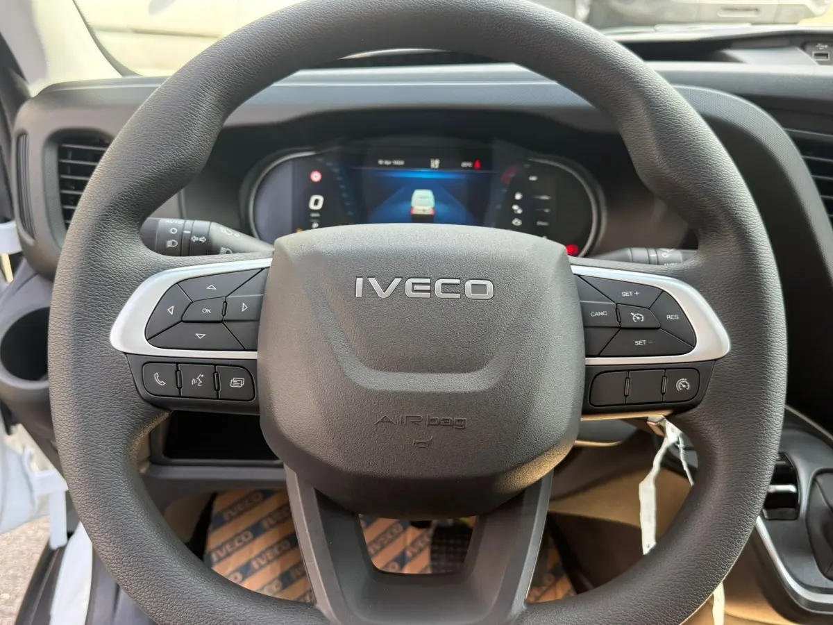 Vue rapprochée du volant noir de l’Iveco Daily 35S18 2026 avec commandes intégrées et tableau de bord numérique.