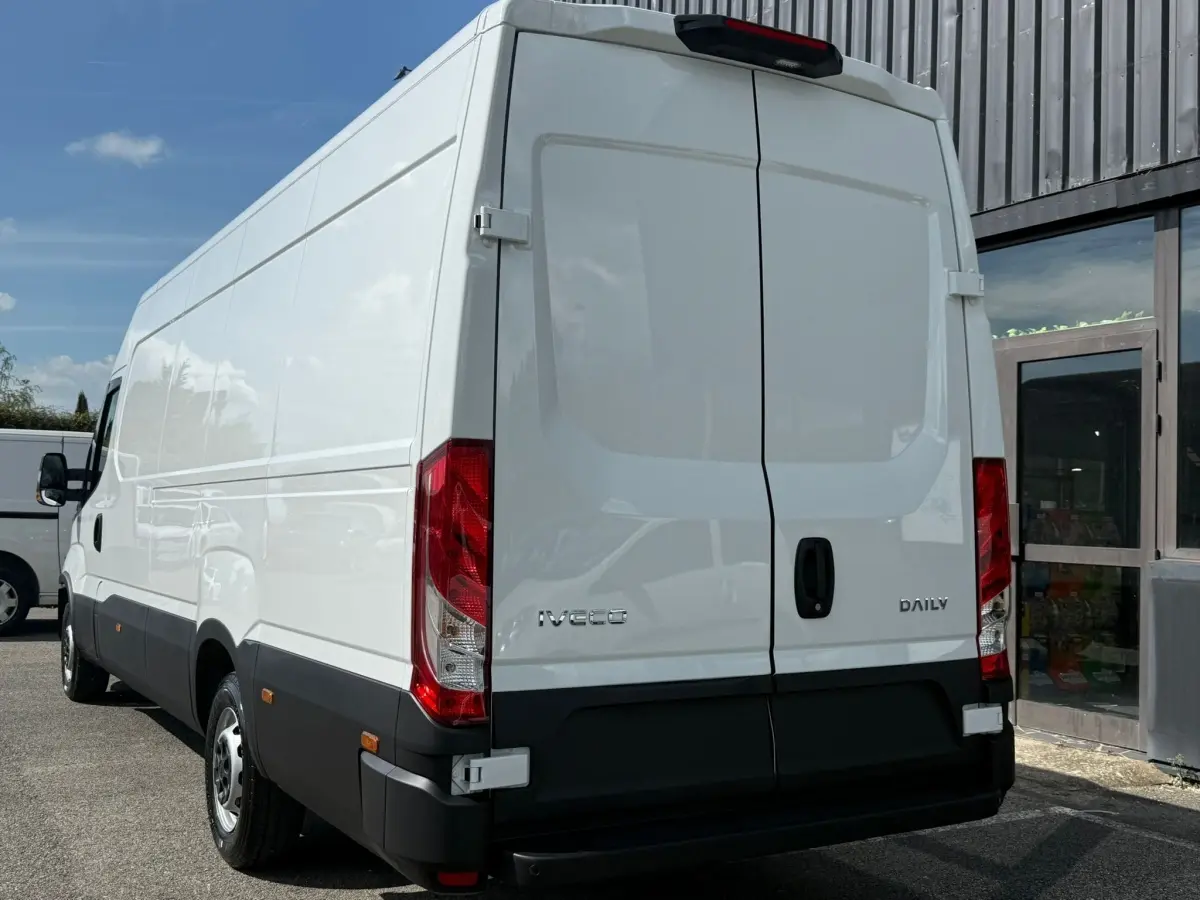 Vue 3/4 arrière droite d’un utilitaire Iveco Daily blanc, portes arrière fermées, feux rouges verticaux visibles.