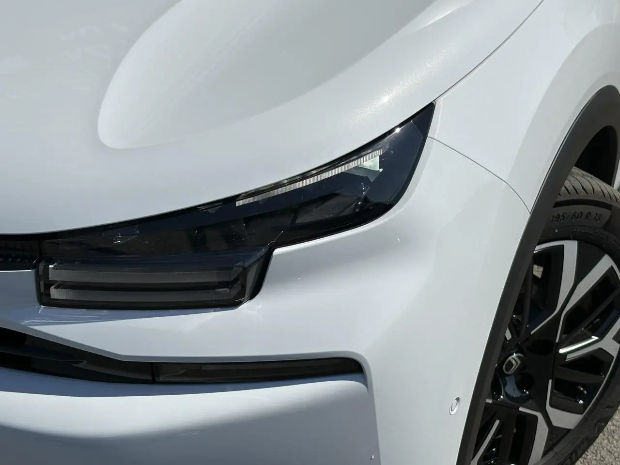 Gros plan sur l’avant droit blanc Okénite du Citroën C4 Hybrid 145 e-DSC6 Max avec phares LED et jante alliage 18 pouces.