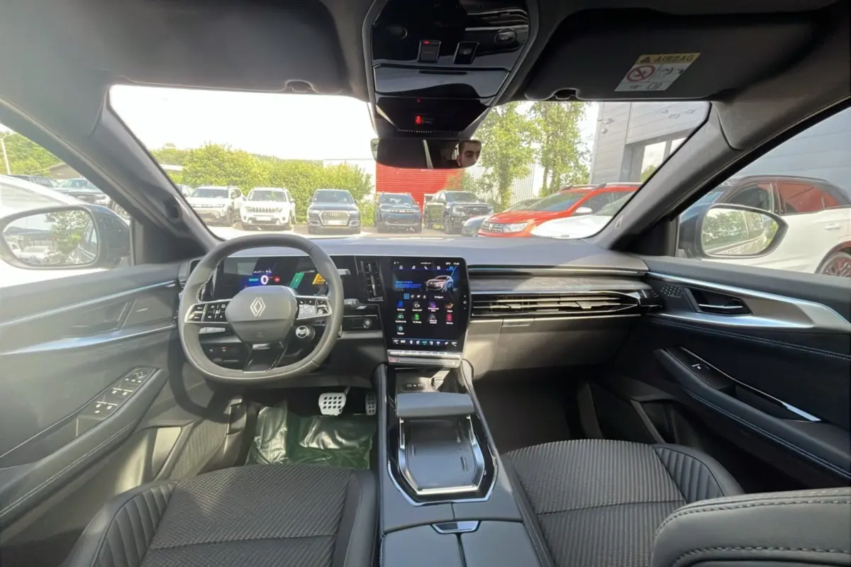 Vue intérieure avant du Renault Austral 200 Esprit Alpine, tableau de bord moderne avec écran tactile vertical et volant multifonctions.