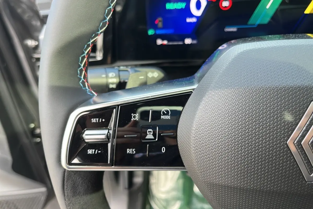 Gros plan sur les commandes à gauche du volant cuir multifonctions du Renault Austral gris schiste avec tableau de bord numérique.