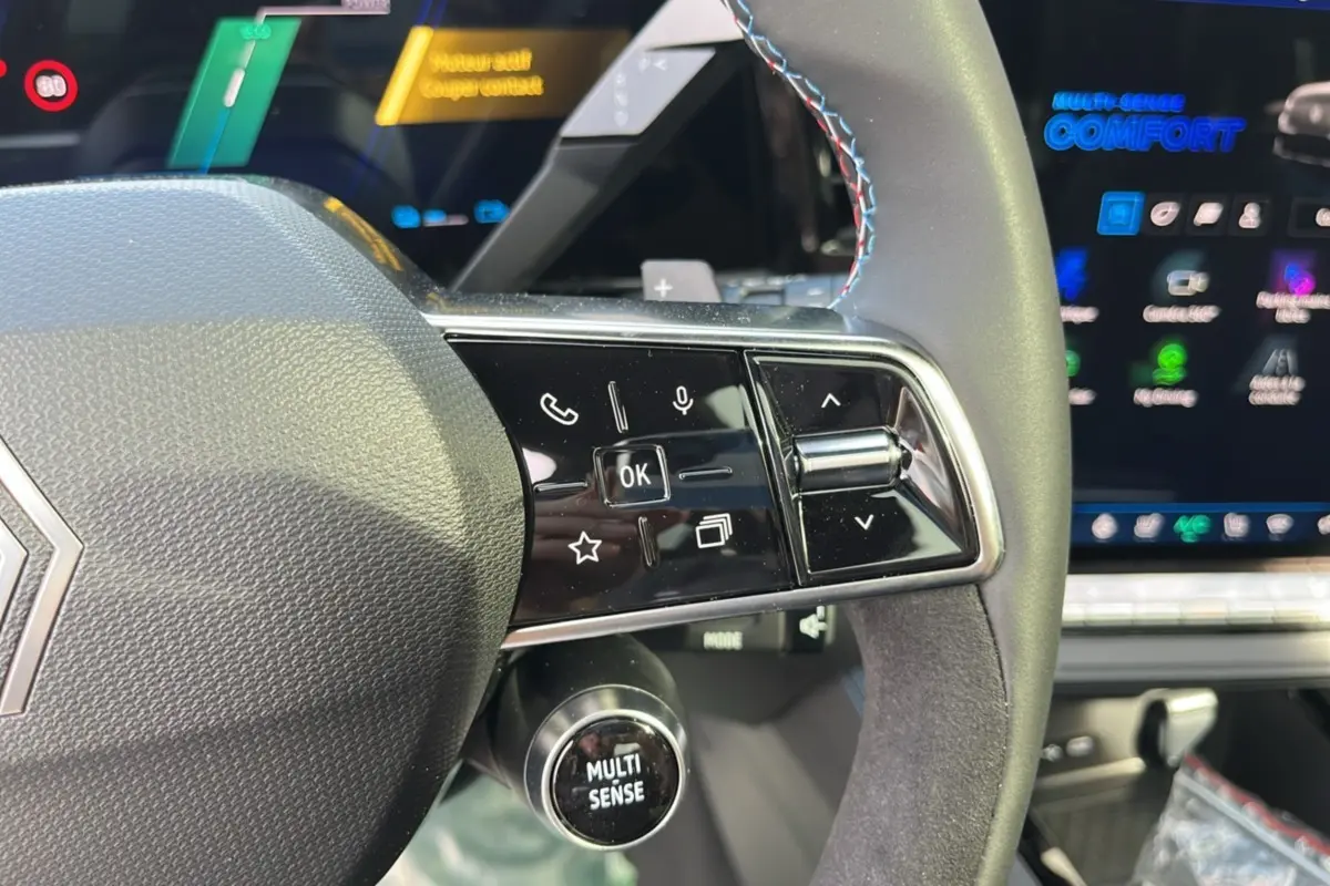 Gros plan sur le volant cuir multifonctions du Renault Austral gris schiste, avec commandes et écran digital en arrière-plan.