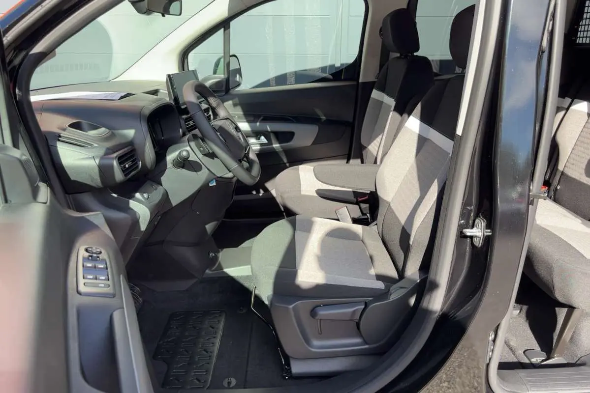 Vue intérieure côté conducteur du Citroën Berlingo noir perla nera, montrant les sièges tissu bicolores et le volant multifonctions.