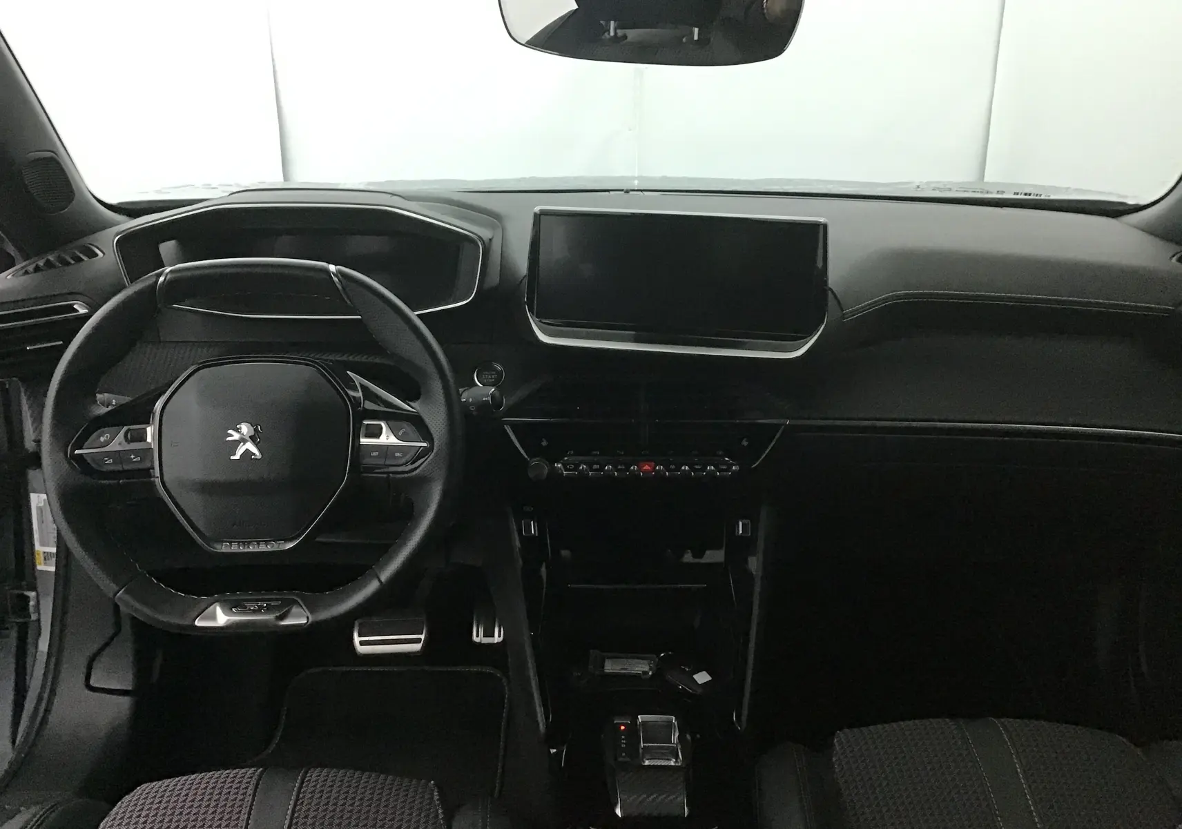 Vue intérieure frontale du tableau de bord et volant du Peugeot 2008 électrique gris Artense/Noir, avec écran tactile central et finitions modernes.