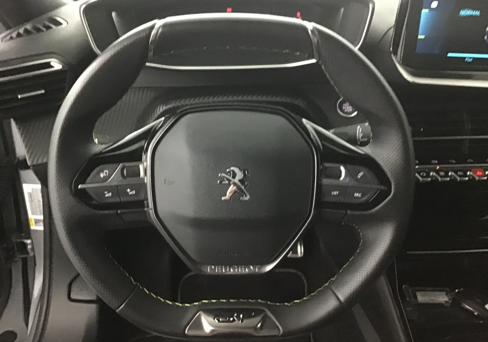 Vue rapprochée du volant cuir noir perforé avec logo Peugeot au centre dans un Peugeot 2008 électrique gris Artense.