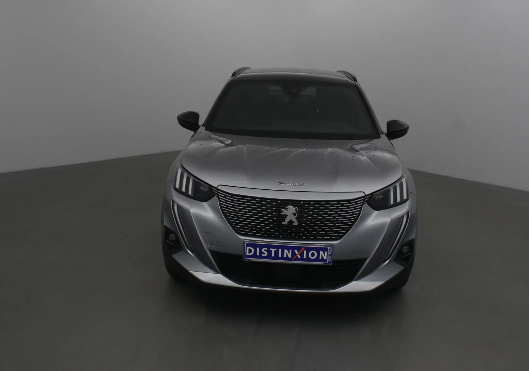 Vue frontale du Peugeot 2008 électrique gris Artense avec calandre noire et logo lion distinctif.