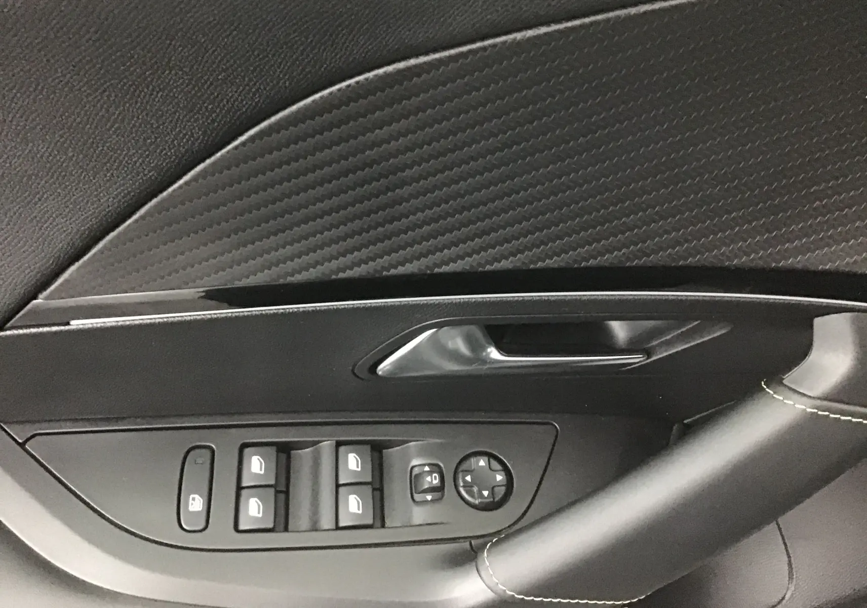 Détail de la porte côté gauche d'une Peugeot 2008 électrique 2022, avec commandes de vitres et revêtement noir texturé.