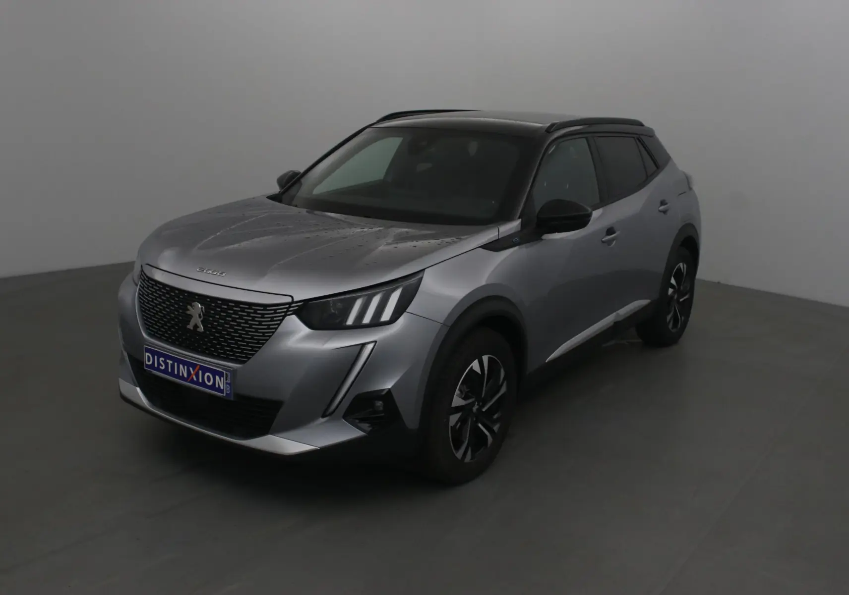 Peugeot 2008 électrique gris Artense avec toit noir, vue 3/4 avant droit en intérieur studio.