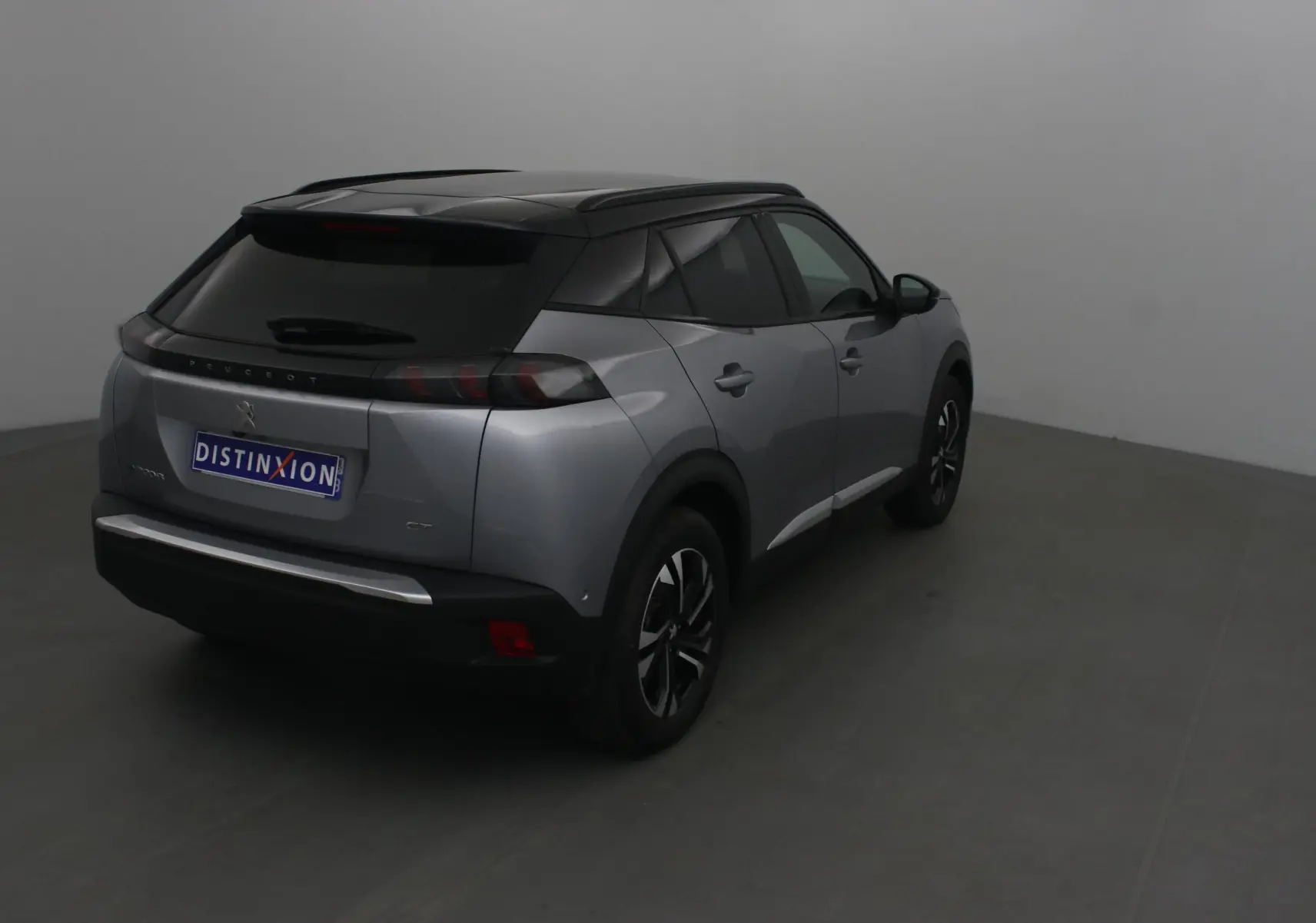 Peugeot 2008 électrique gris Artense avec toit noir, vue 3/4 arrière droit dans un studio neutre.
