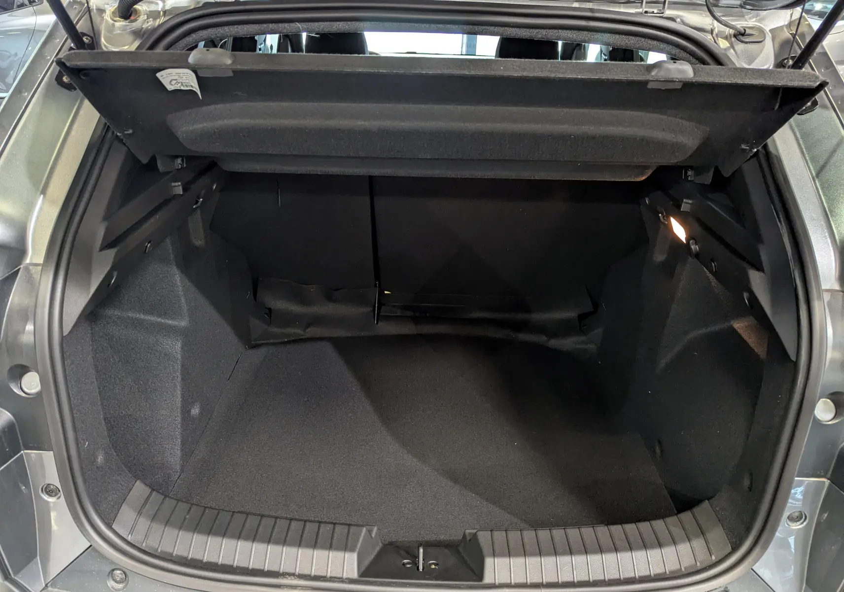Coffre ouvert du Dacia Duster Mild Hybrid 130 CH 4x2 EXTRÊME gris schiste, montrant l'espace de rangement intérieur.