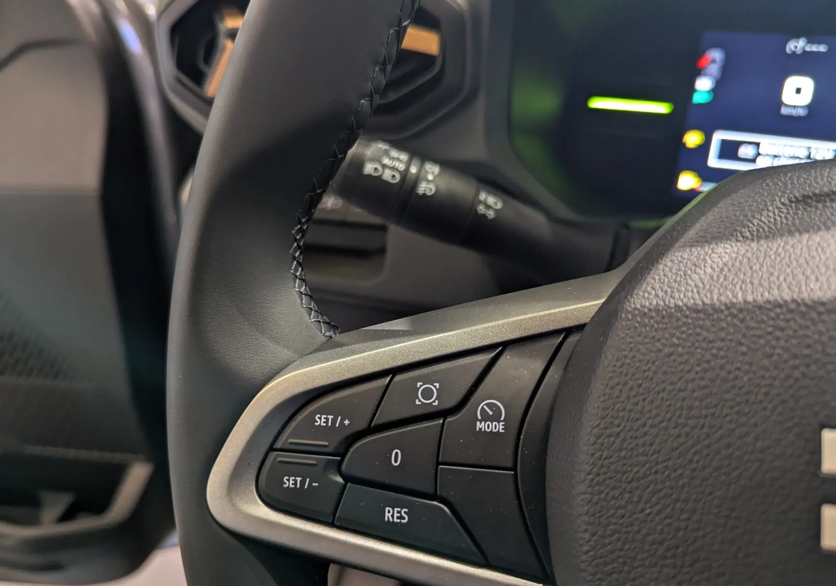 Gros plan sur les commandes au volant du Dacia Duster Mild Hybrid 130 CH 4x2 EXTRÊME, intérieur noir moderne.