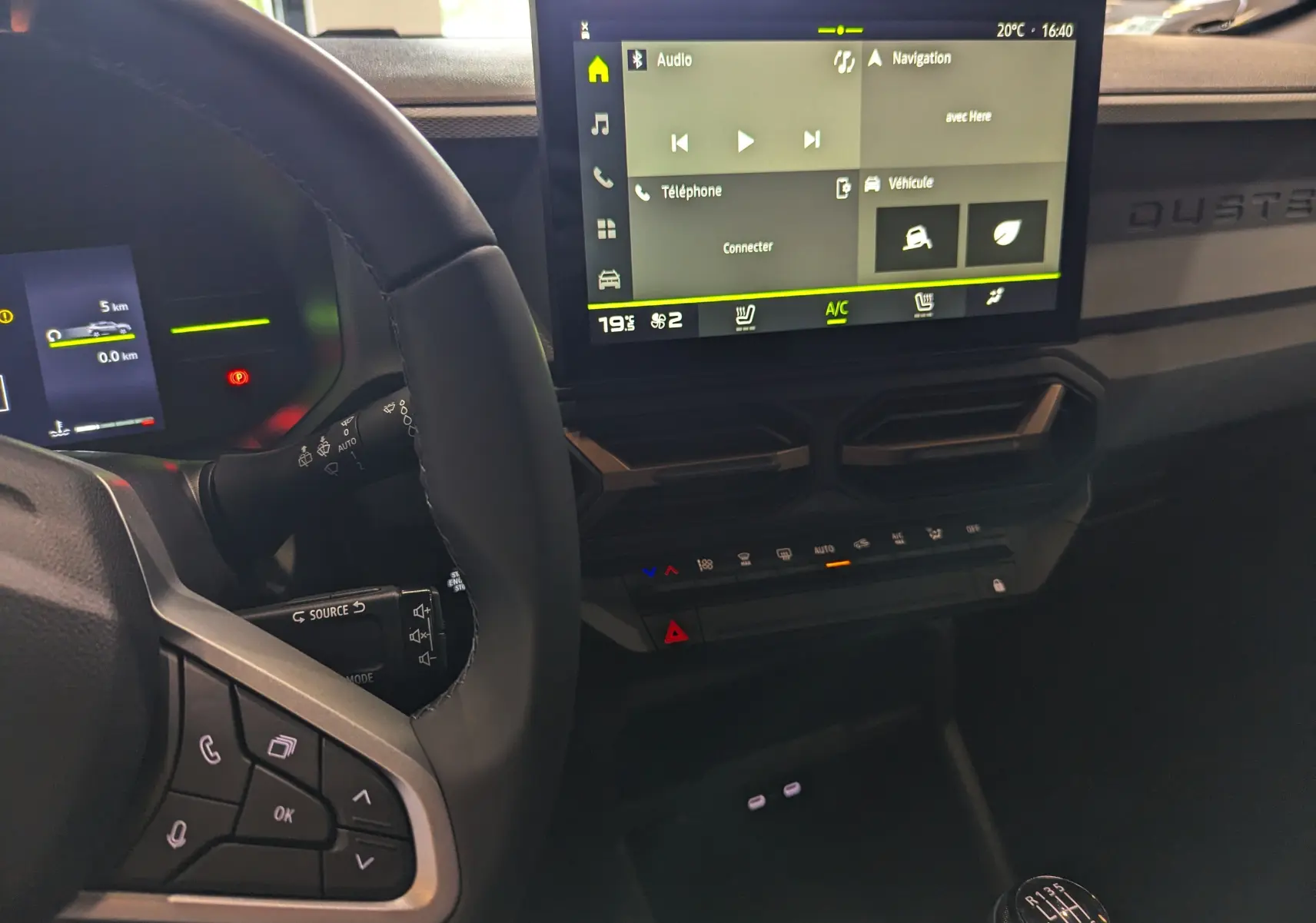 Vue intérieure du tableau de bord du Dacia Duster 2025, avec écran tactile central et volant multifonction noir.