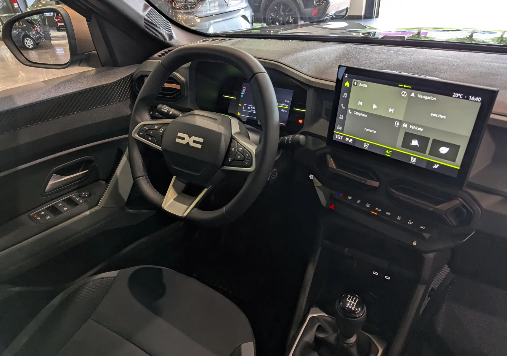 Vue intérieure côté conducteur du Dacia Duster 2025 avec tableau de bord numérique et écran tactile central.