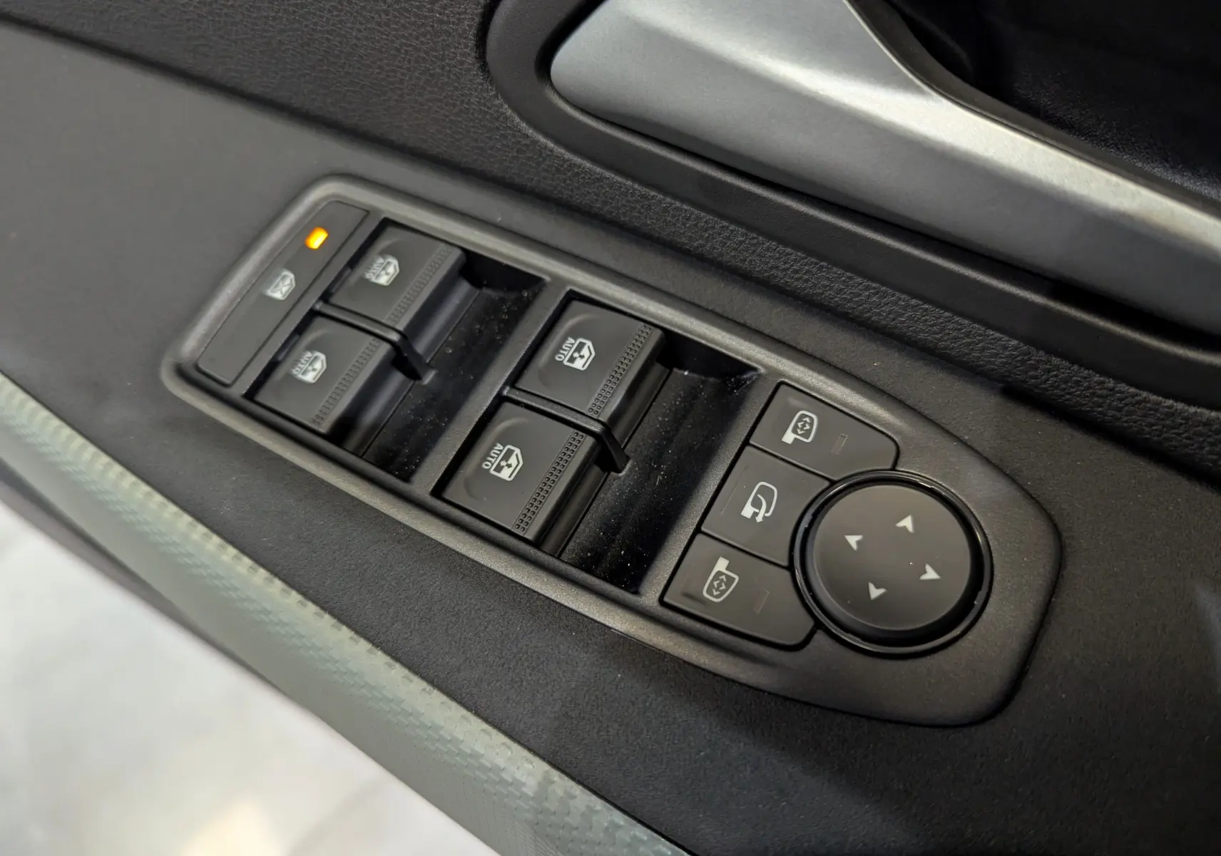 Commande des vitres électriques et réglage des rétroviseurs sur la porte côté conducteur du Dacia Duster gris Schiste.