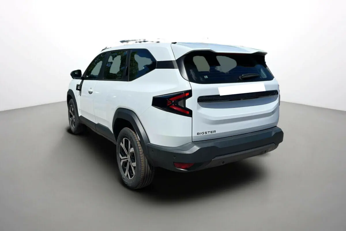 Vue 3/4 arrière droite d'un Dacia Bigster blanc glacier avec jantes alu 17 pouces et barres de toit noires.