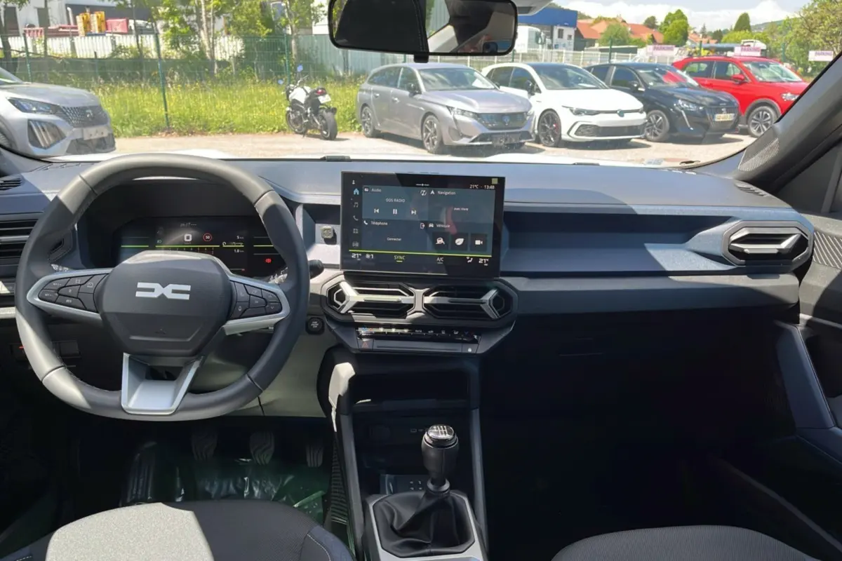 Vue intérieure du tableau de bord du Dacia Bigster 2025 avec volant multifonction, écran tactile et levier de vitesses manuel.