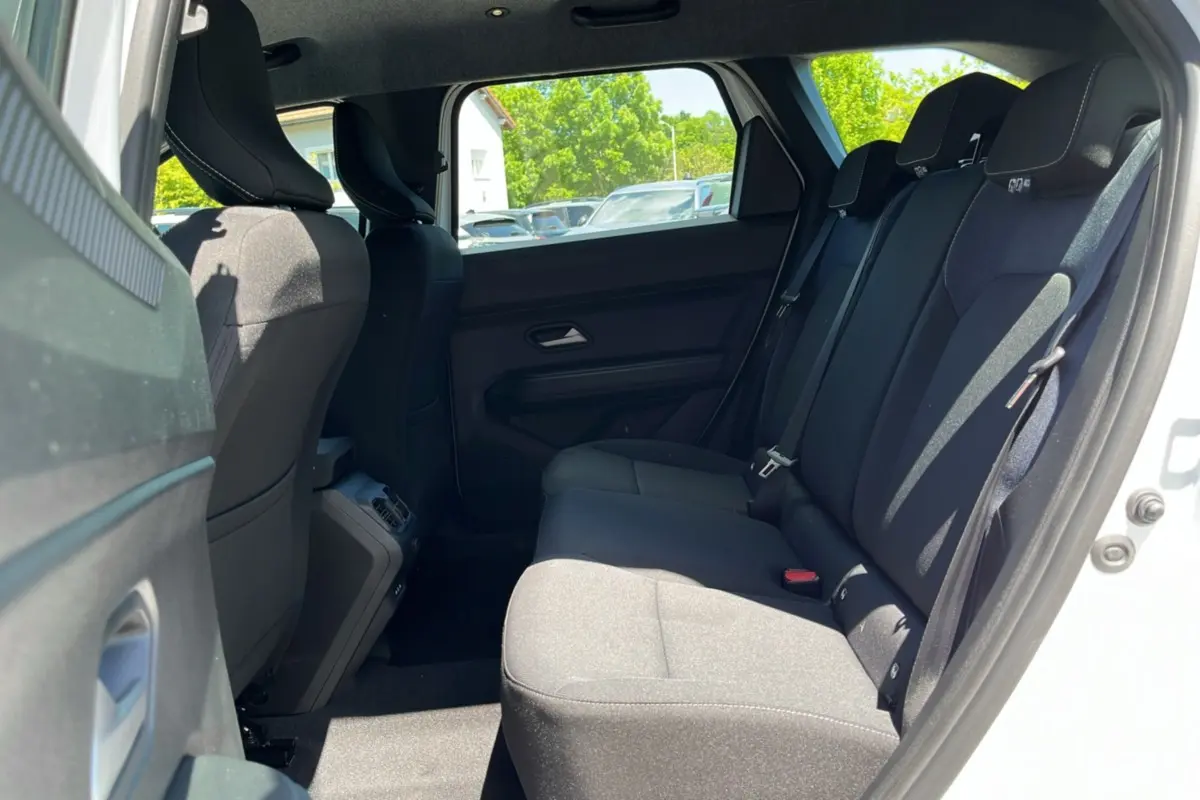 Vue latérale droite de l'habitacle arrière du Dacia Bigster blanc glacier, montrant les sièges noirs et l'ouverture de porte.