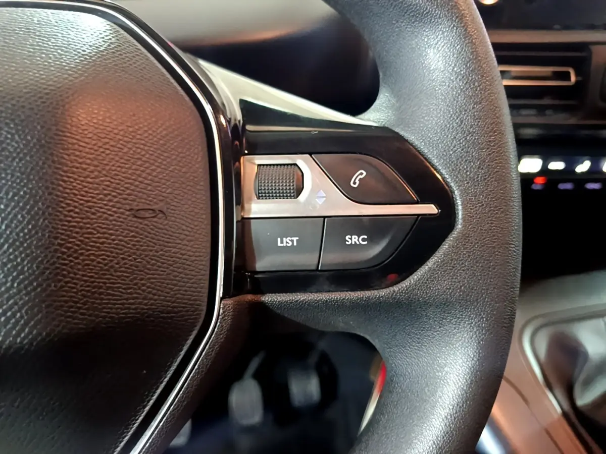 Gros plan sur les commandes du volant côté droit du Peugeot Rifter marron, avec boutons de téléphone et réglages audio.