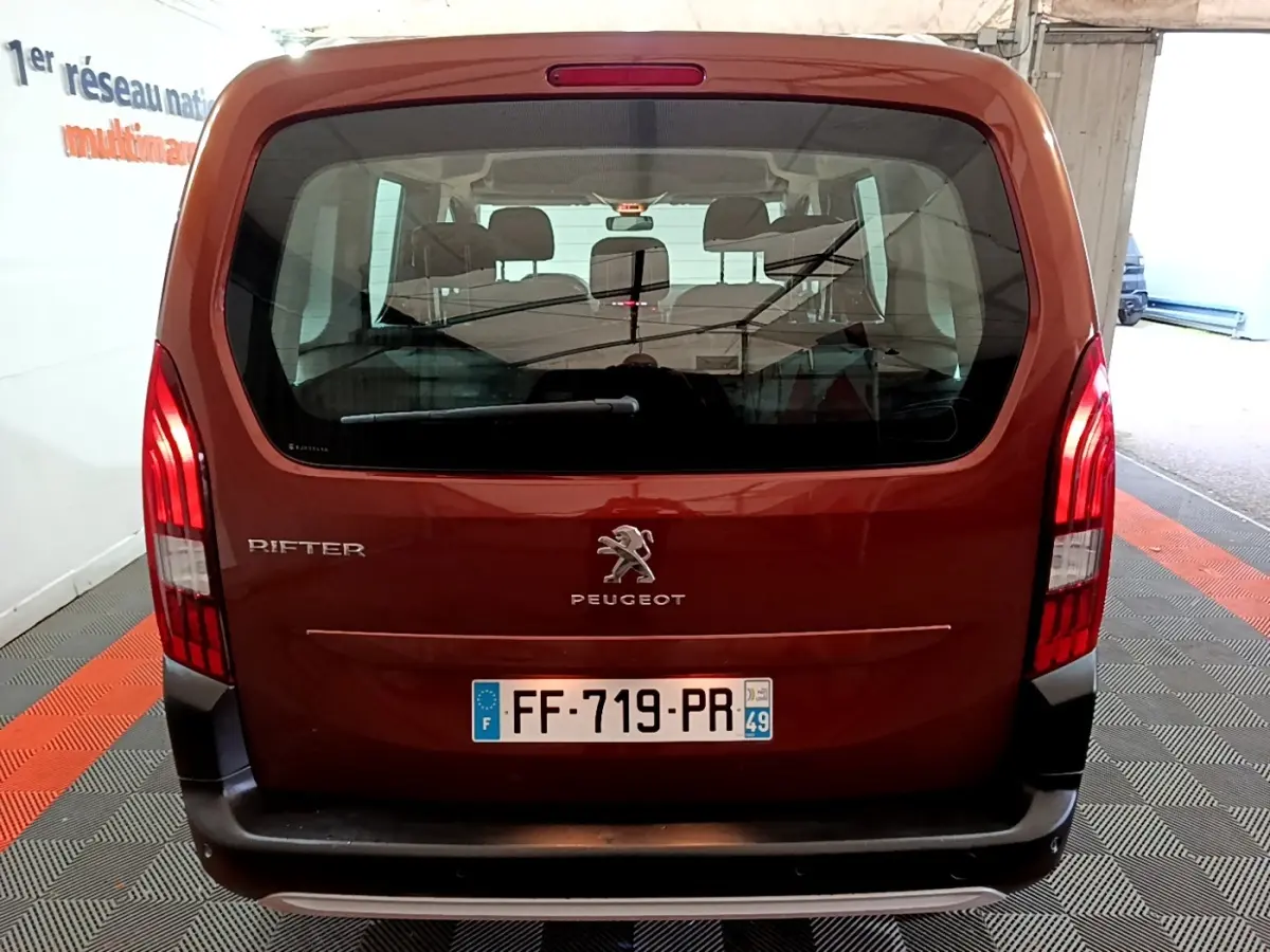 Vue arrière d'un Peugeot Rifter marron 2019 avec logo et feux verticaux allumés dans un garage.