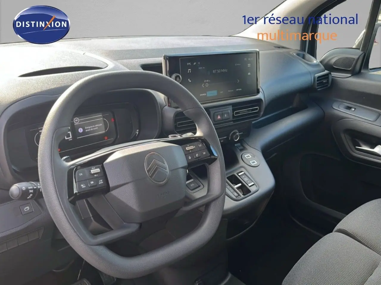 Vue intérieure côté conducteur du Citroën Berlingo 2025, tableau de bord noir avec écran tactile et volant multifonction.