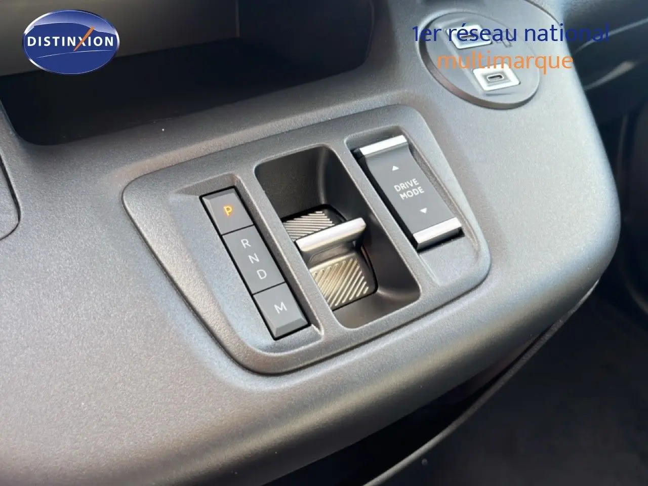 Gros plan sur la console centrale du Citroën Berlingo blanc, montrant la commande de boîte automatique et le bouton Drive Mode.