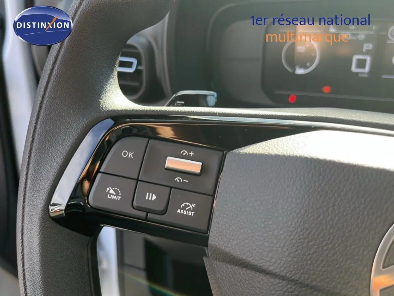 Gros plan sur les commandes au volant côté gauche du Citroën Berlingo blanc Icy, intérieur noir avec tableau de bord numérique.