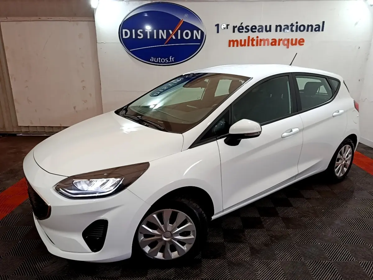 Vue 3/4 avant droite d'une Ford Fiesta blanche 2022 avec phares LED et jantes alliage dans un showroom.