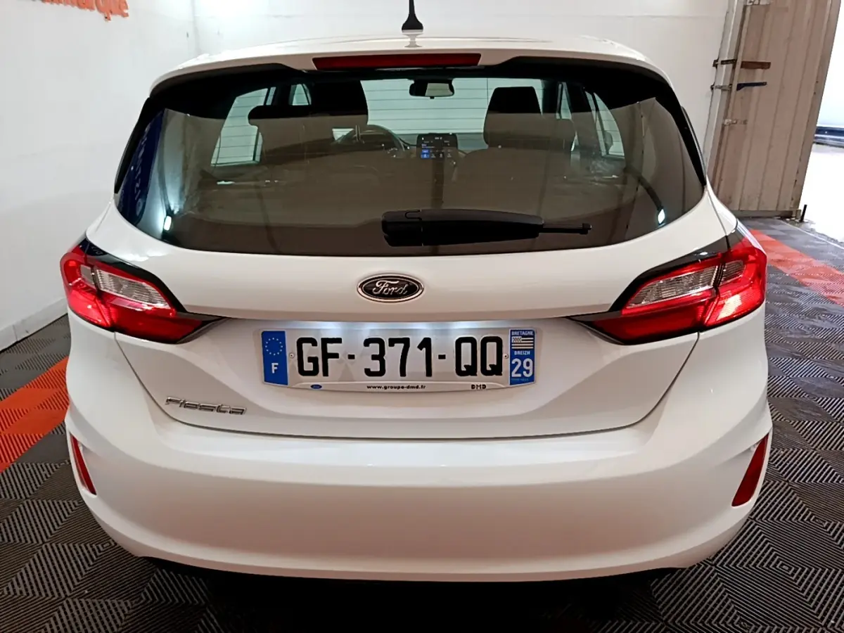Vue arrière d'une Ford Fiesta blanche 2022 avec feux arrière LED et plaque d'immatriculation française visible.