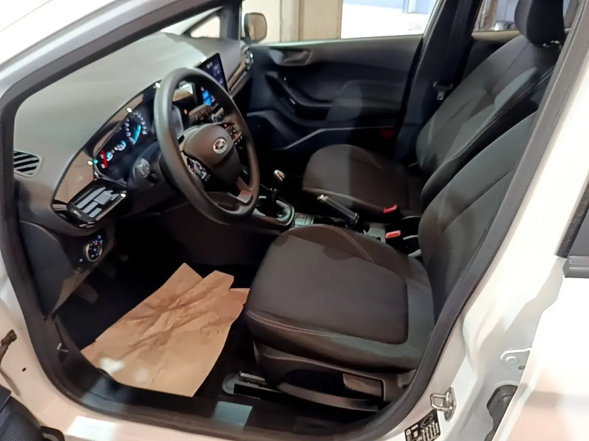 Vue intérieure côté conducteur de la Ford Fiesta blanche 2022, montrant sièges noirs et tableau de bord digital.