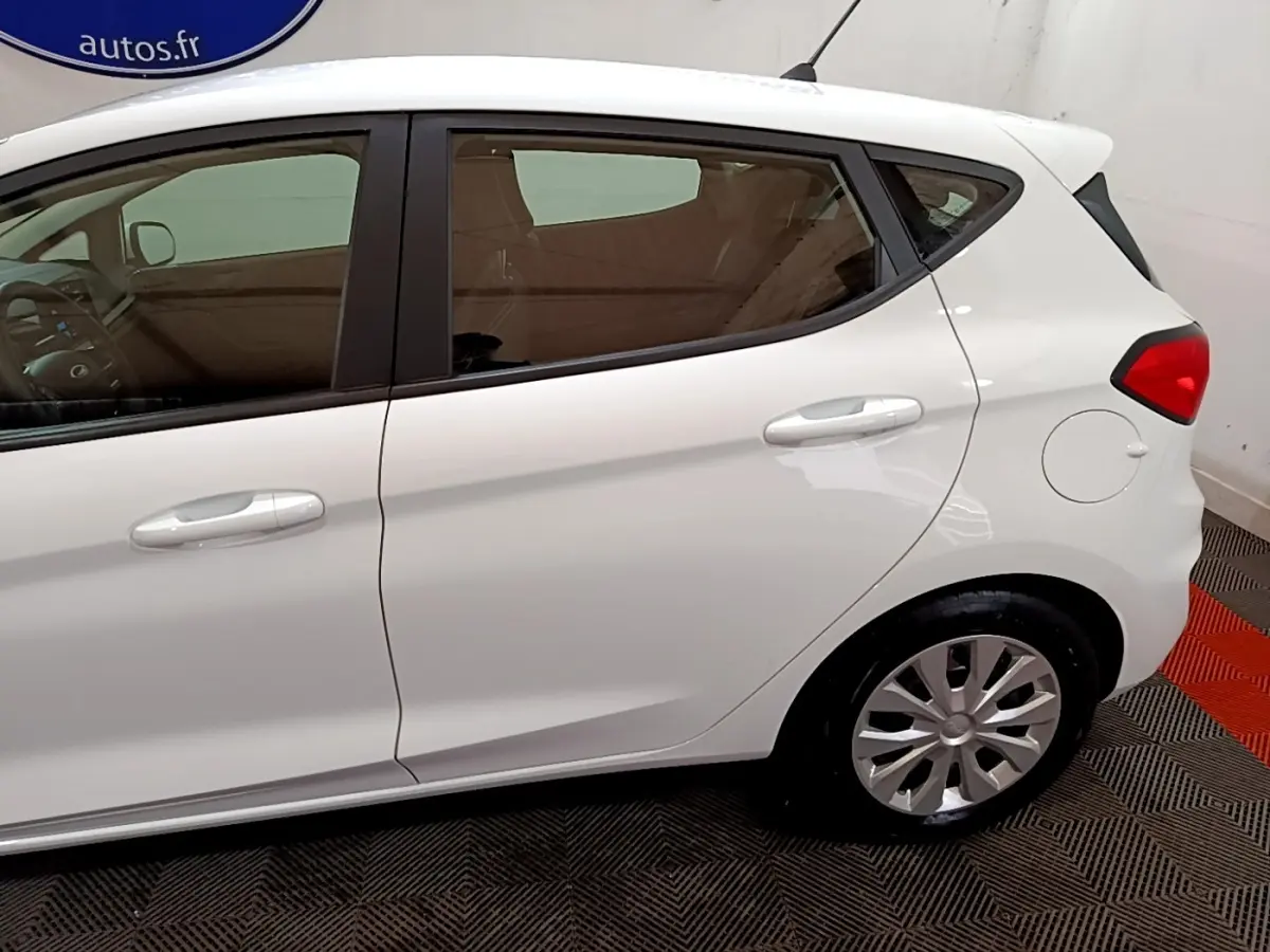Vue latérale droite d'une Ford Fiesta blanche 2022, mettant en valeur les portières et la roue arrière.