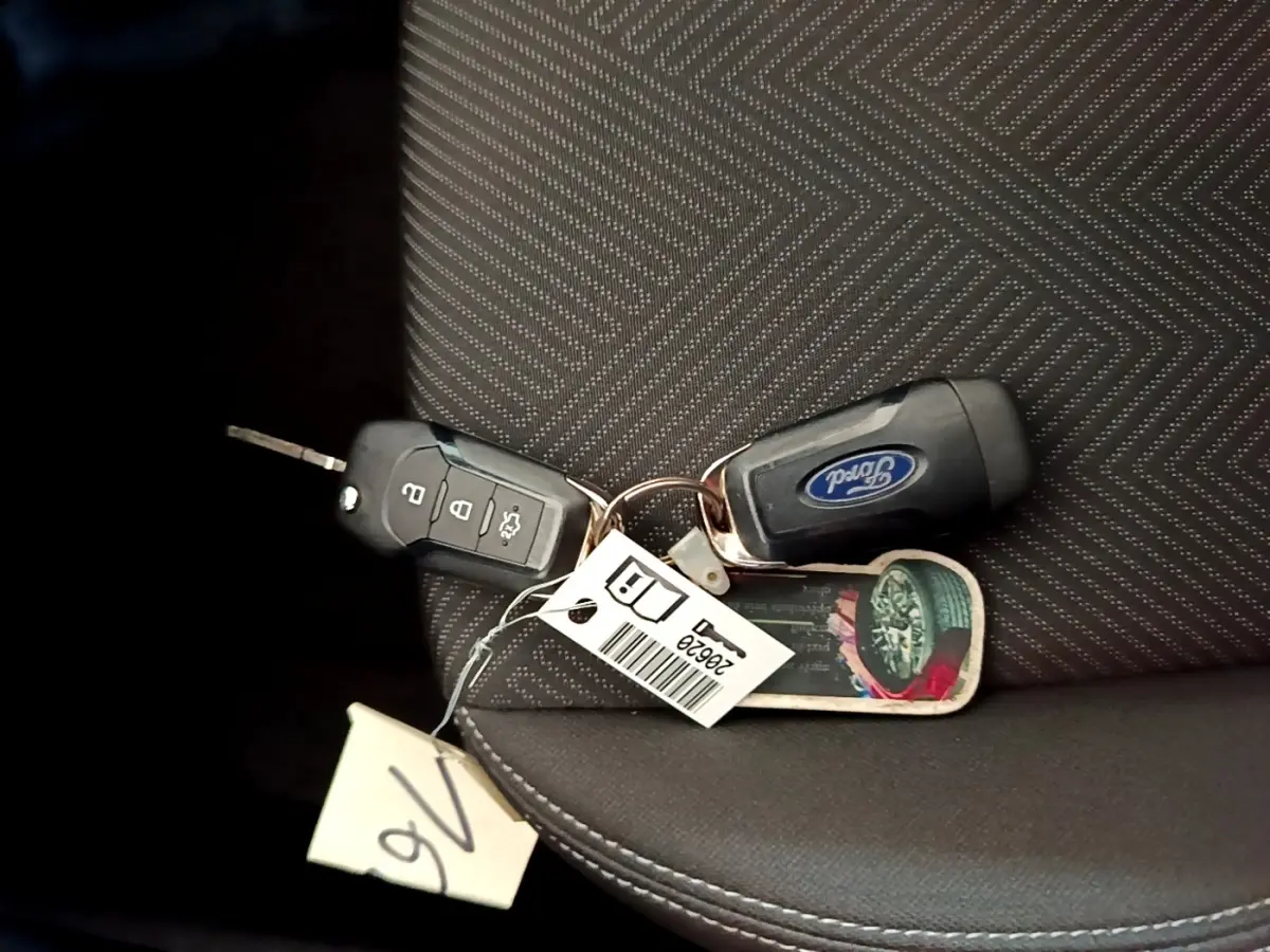 Gros plan sur deux clés Ford posées sur un siège tissu gris foncé avec motifs géométriques.