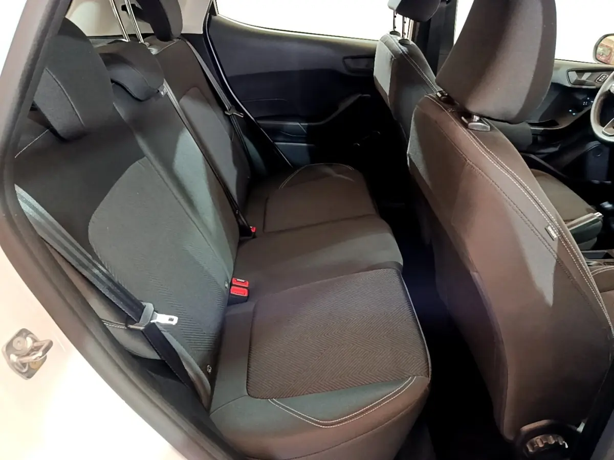 Vue intérieure côté gauche montrant la banquette arrière noire de la Ford Fiesta blanche 2022, avec sièges et ceintures visibles.