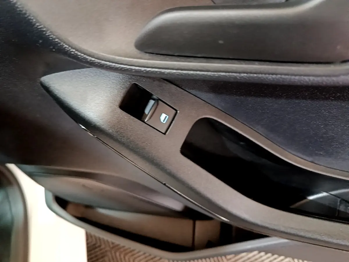 Gros plan sur le bouton de commande de lève-vitre côté conducteur dans l’habitacle noir de la Ford Fiesta blanche.