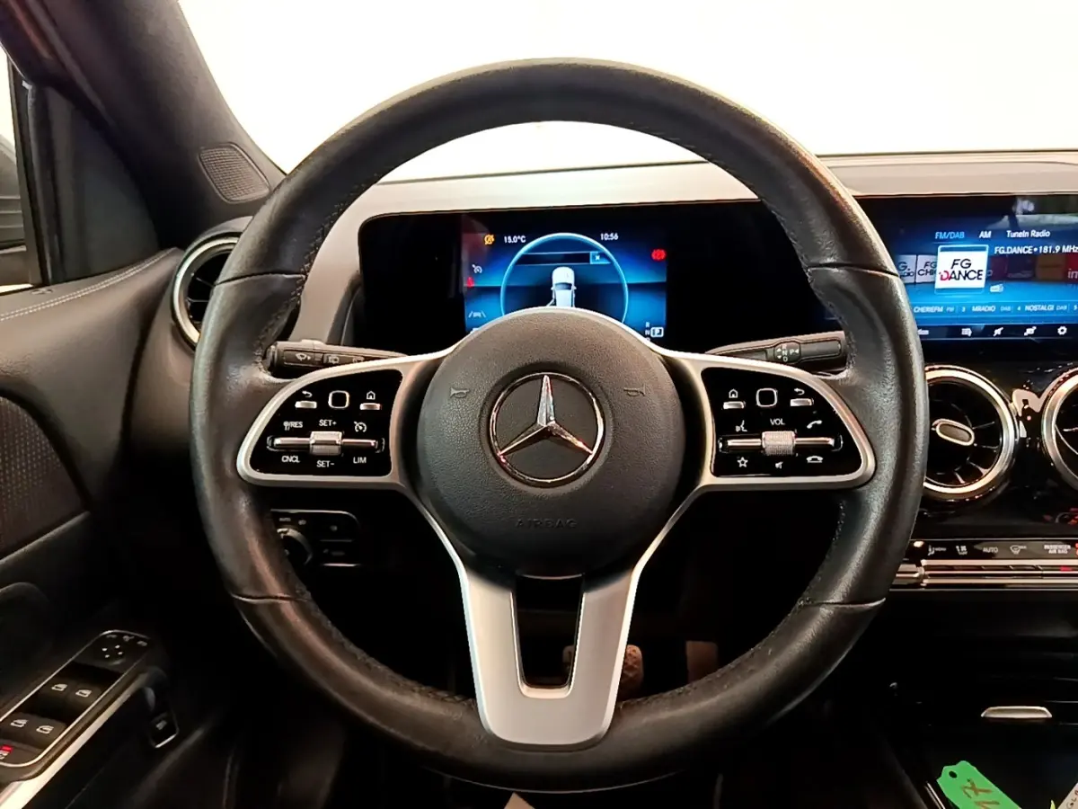 Vue intérieure centrée sur le volant cuir et alu d’un Mercedes GLB 200 d Business Line avec tableau de bord digital.
