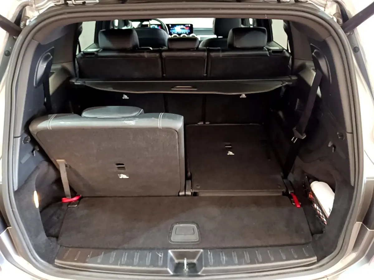 Coffre ouvert d’un Mercedes GLB 200 d gris foncé, montrant la 3ème rangée de sièges rabattable à distance, côté droit abaissé.