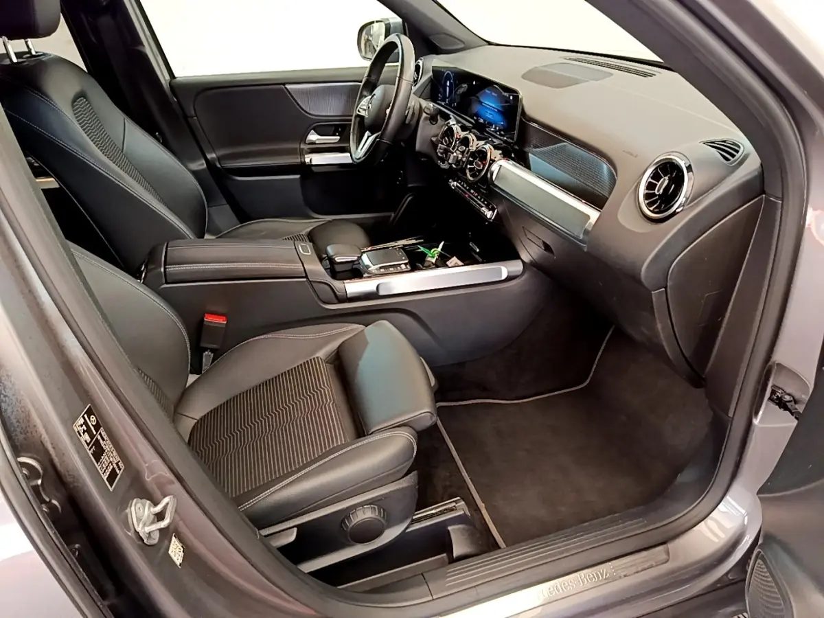 Vue intérieure côté passager avant du Mercedes GLB 200 d Business Line gris foncé, avec tableau de bord digital et sièges en cuir noir.