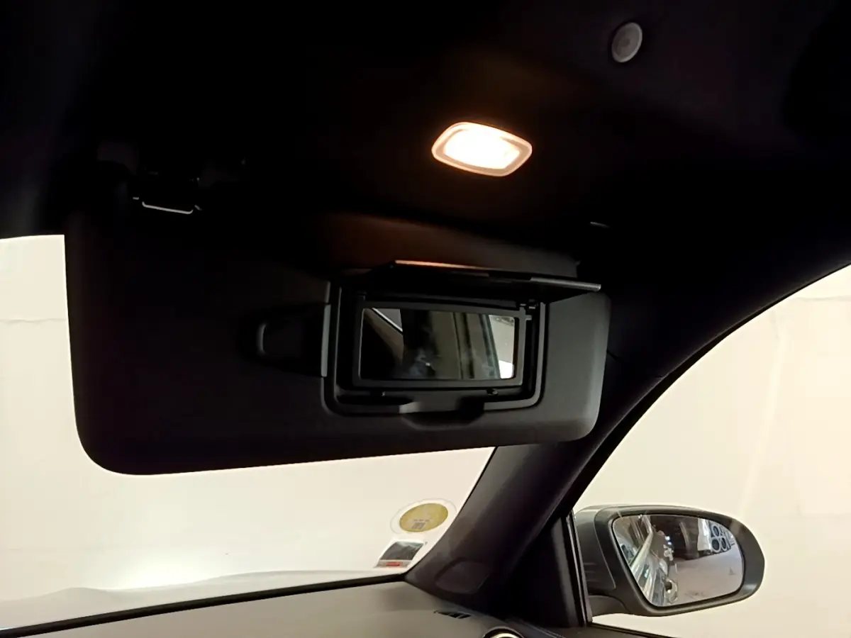 Détail de miroir de courtoisie sur pare-soleil côté conducteur dans l’habitacle sombre d’un Mercedes GLB gris foncé.