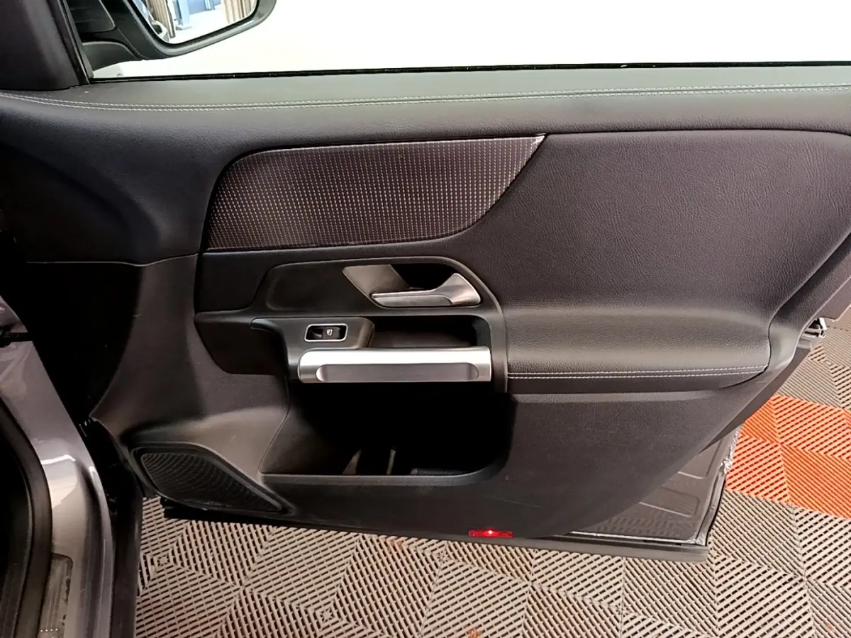 Vue intérieure côté gauche de la porte avant gris foncé du Mercedes GLB 200 d Business Line avec poignée argentée.