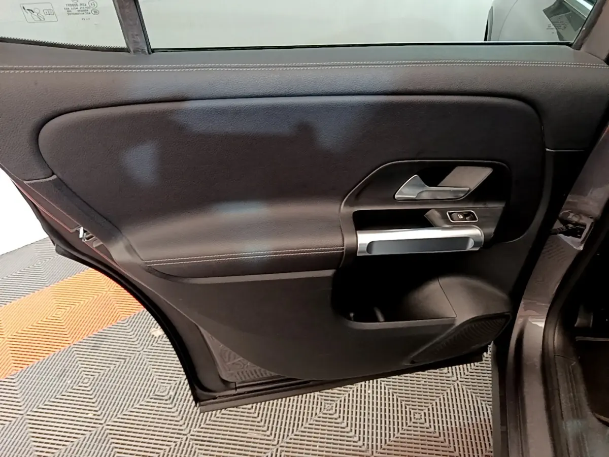 Vue intérieure de la porte arrière droite du Mercedes GLB 200 d Business Line gris foncé, avec poignée argentée et commandes électriques.