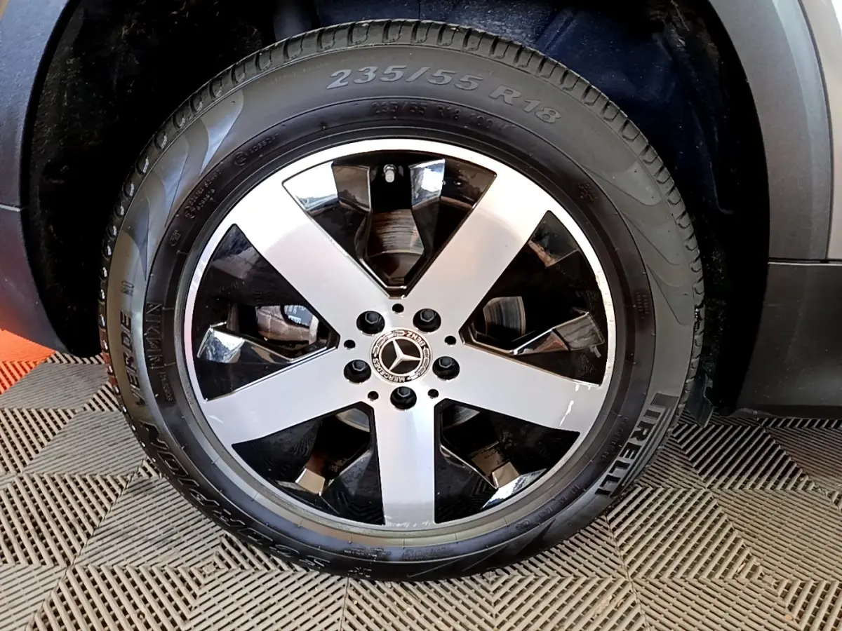 Gros plan sur la roue avant droite d’un Mercedes GLB 200 d gris foncé avec jante alliage à cinq branches bicolores.