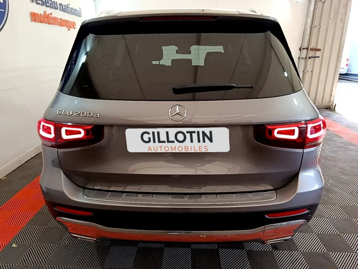 Vue arrière d'un Mercedes GLB 200 d gris foncé avec feux LED allumés dans un showroom.