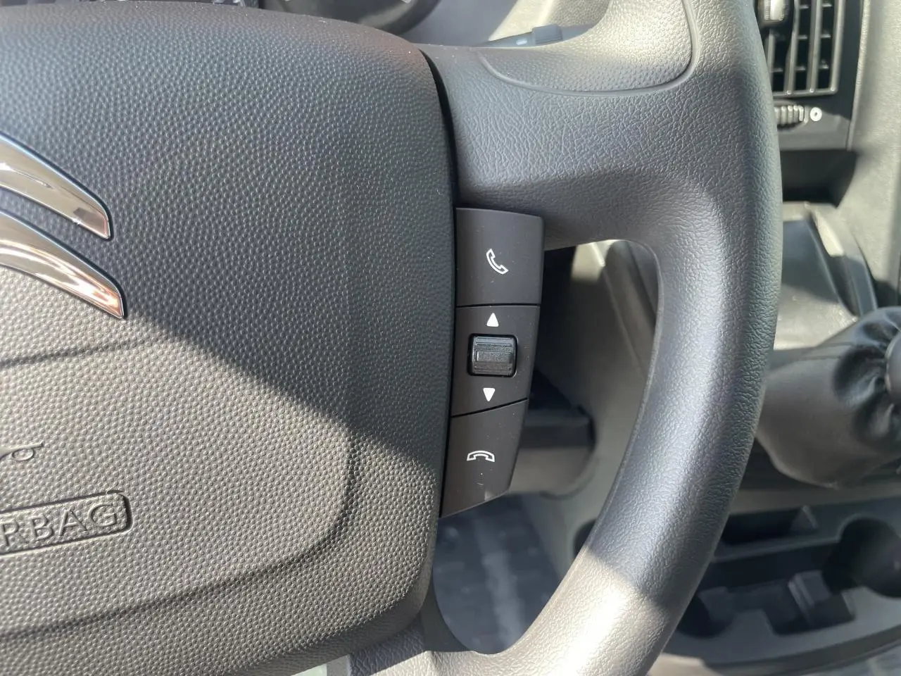 Gros plan sur le volant noir du Citroën Jumper 2023 avec commandes audio intégrées et levier de vitesses manuel visible.