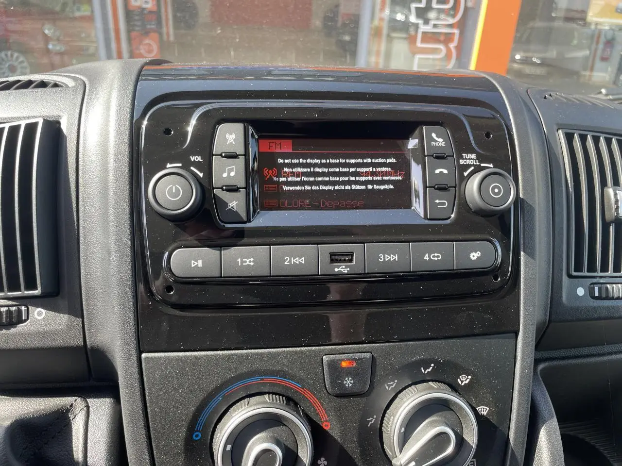 Vue rapprochée du tableau de bord noir du Citroën Jumper 2023, avec système audio et commandes de climatisation.