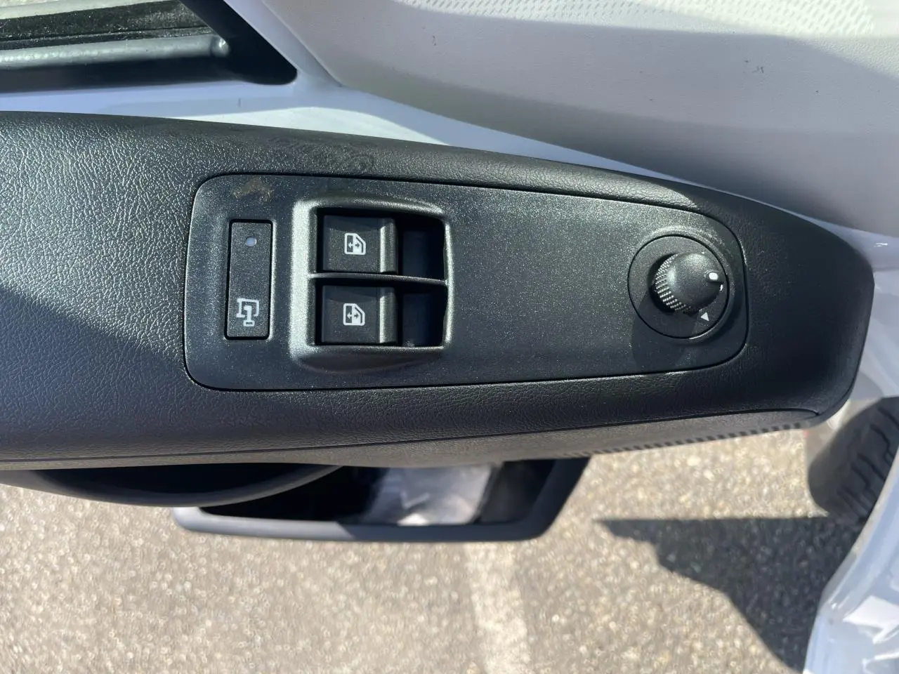 Gros plan sur les commandes de lève-vitres et réglage des rétroviseurs côté conducteur du Citroën Jumper blanc 2023.