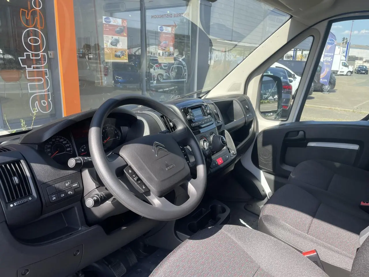 Vue intérieure côté conducteur du Citroën Jumper blanc 2023, montrant le volant, tableau de bord et banquette passager biplace.
