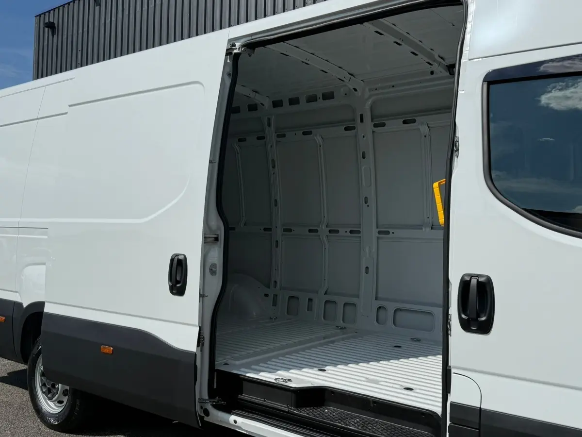 IVECO Daily blanc vu de côté droit avec porte coulissante ouverte montrant l'espace de chargement vide.
