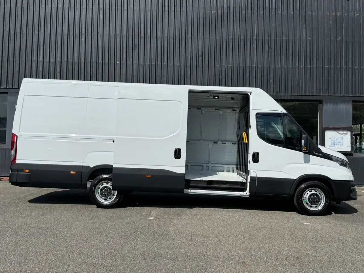 Vue latérale droite d’un Iveco Daily blanc 2026 avec porte coulissante ouverte montrant l’espace de chargement vide.