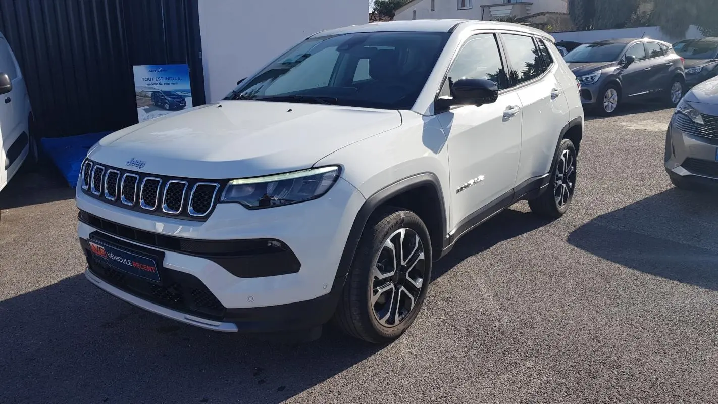 Jeep Compass blanc vue 3/4 avant droit, jantes alliage 18 pouces et calandre caractéristique à sept fentes.