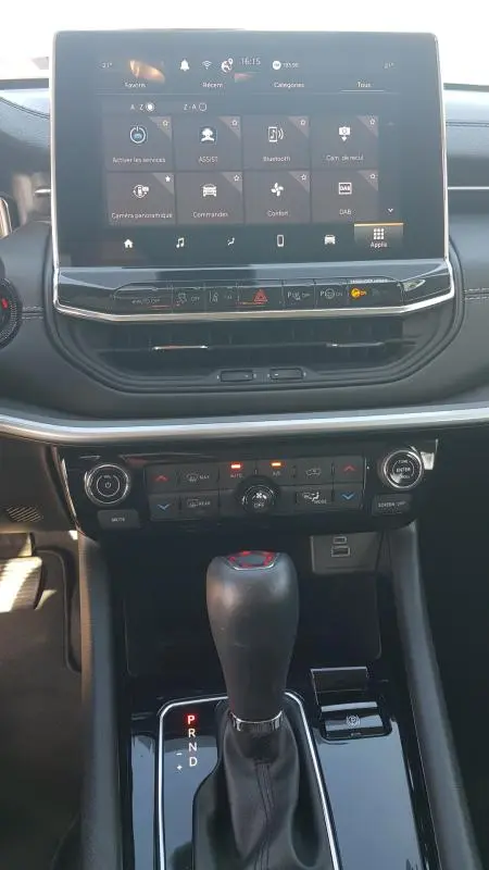 Vue rapprochée de la console centrale du Jeep Compass blanc 2024, avec écran tactile et levier de boîte auto.