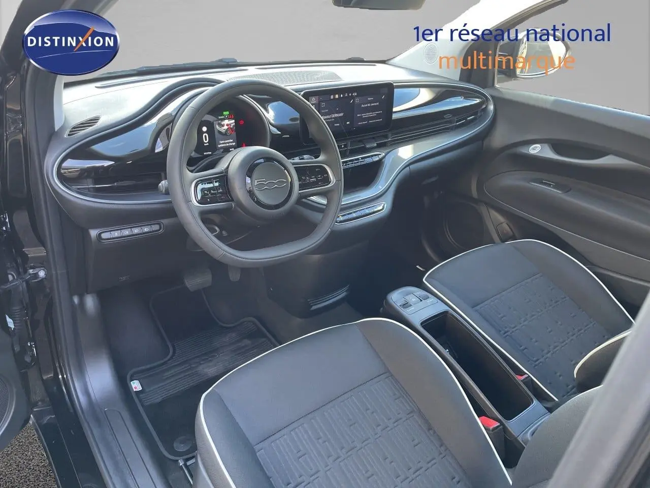 Vue intérieure côté conducteur de la Fiat 500 électrique 2023 noir onyx, avec tableau de bord numérique et sièges tissu noirs.